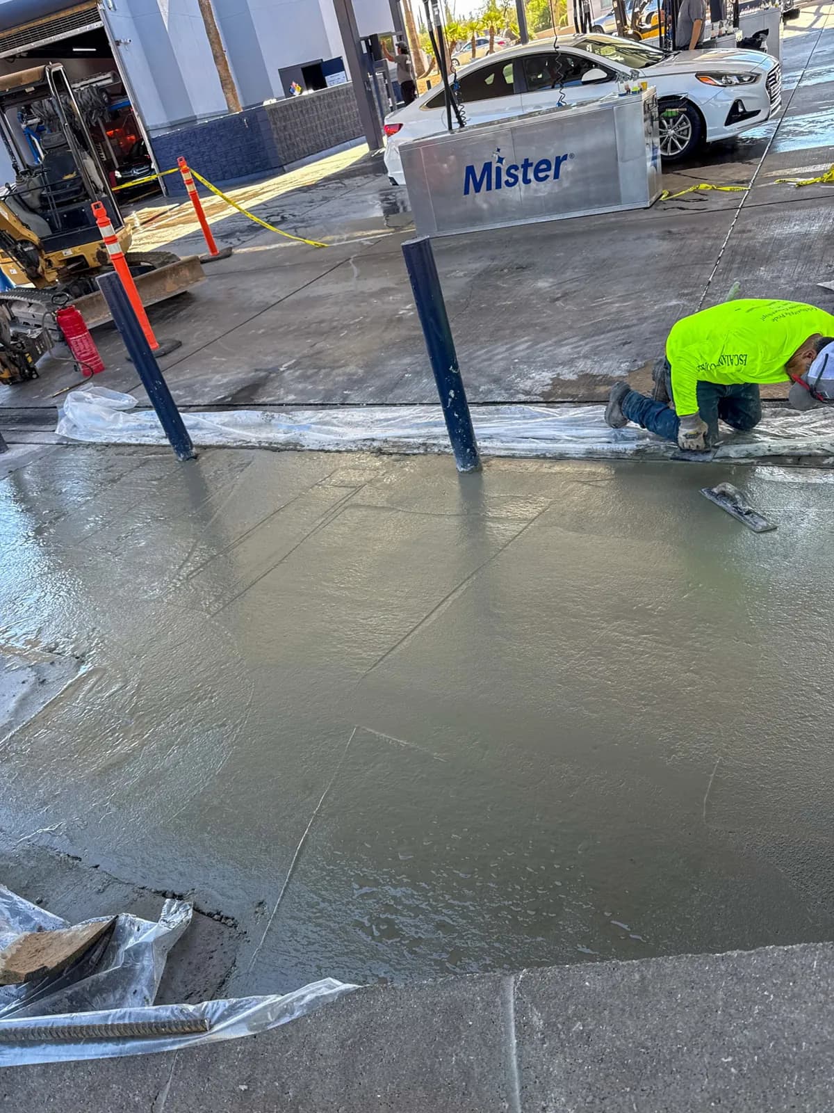 Finishing a fresh concrete pour around bollards at a commercial car wash